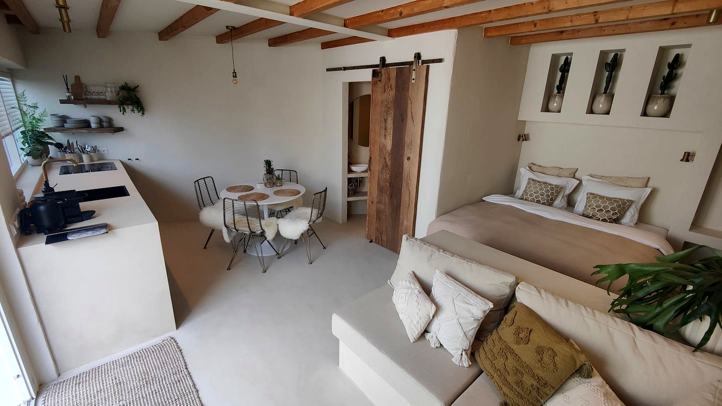 Overzicht van de woonruimte met bed, bank en schuifdeur van oud hout