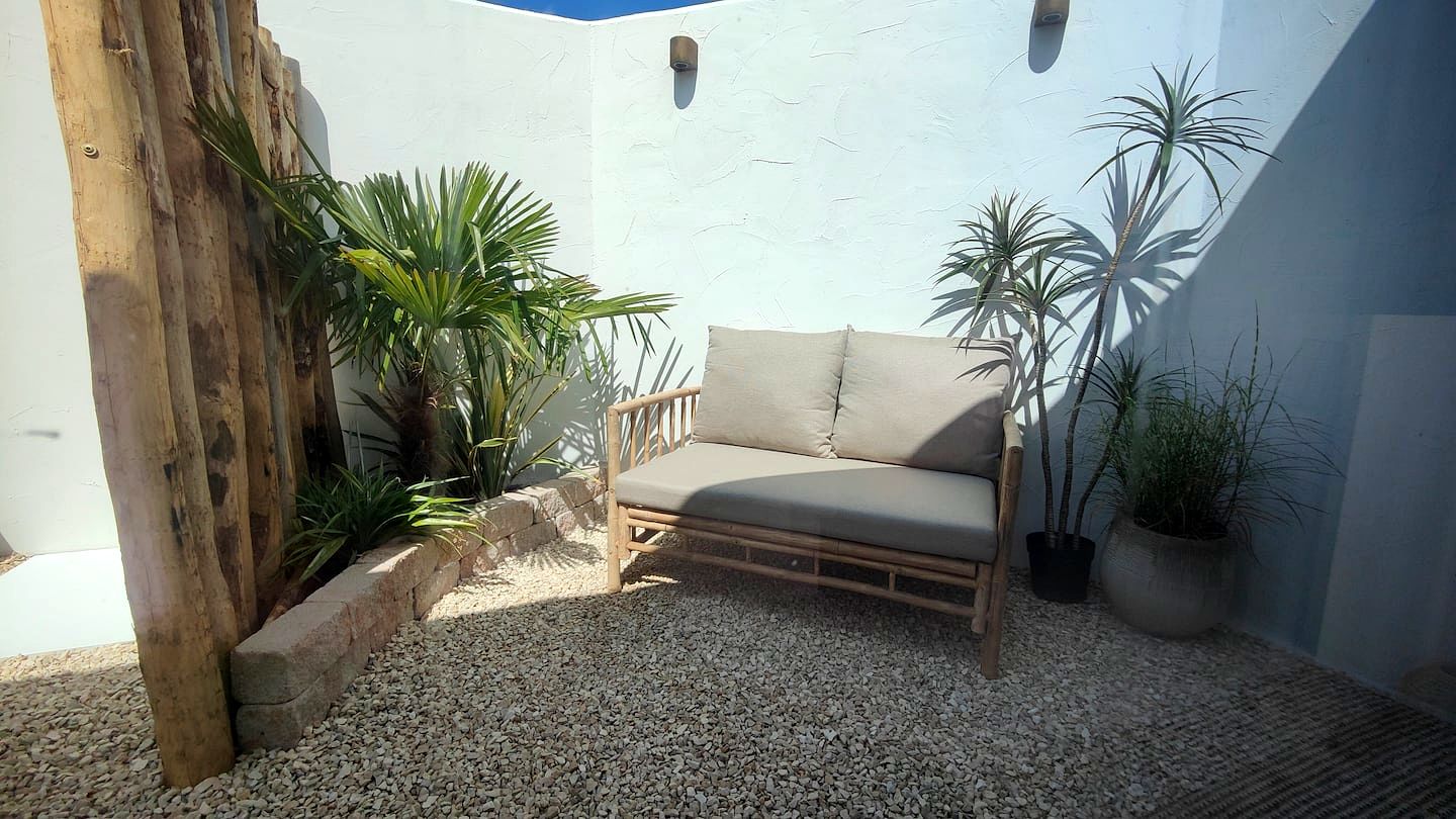 Het terras met bamboe loungebank tussen de palmen